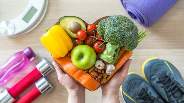 A heart shaped bowl of broccoli, apples, and pineapple.