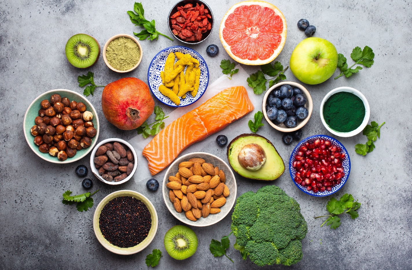 Selection of healthy products and superfoods: salmon, fruit, vegetables, berries, goji, spirulina, matcha, quinoa, chia seeds, nuts. Clean eating concept, gray background, top view, close up